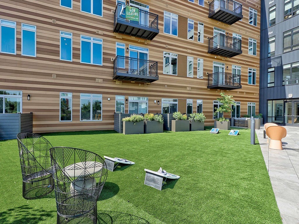 a yard in front of a building with green grass and chairs
